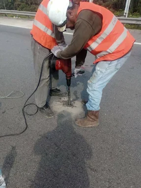 Geocon technicians drilling an injection hole through a road pavement